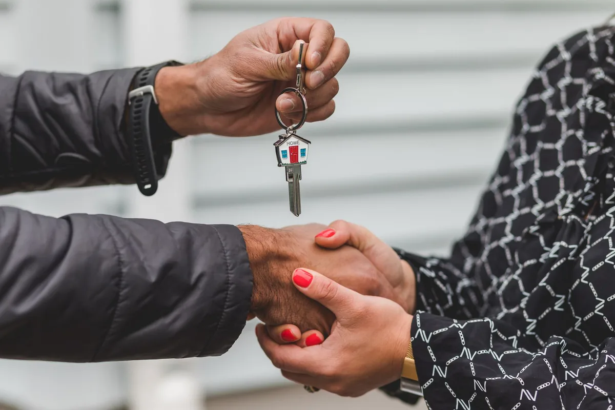 Entrega de las llaves de una vivienda con un apretón de manos tras firmar la compraventa