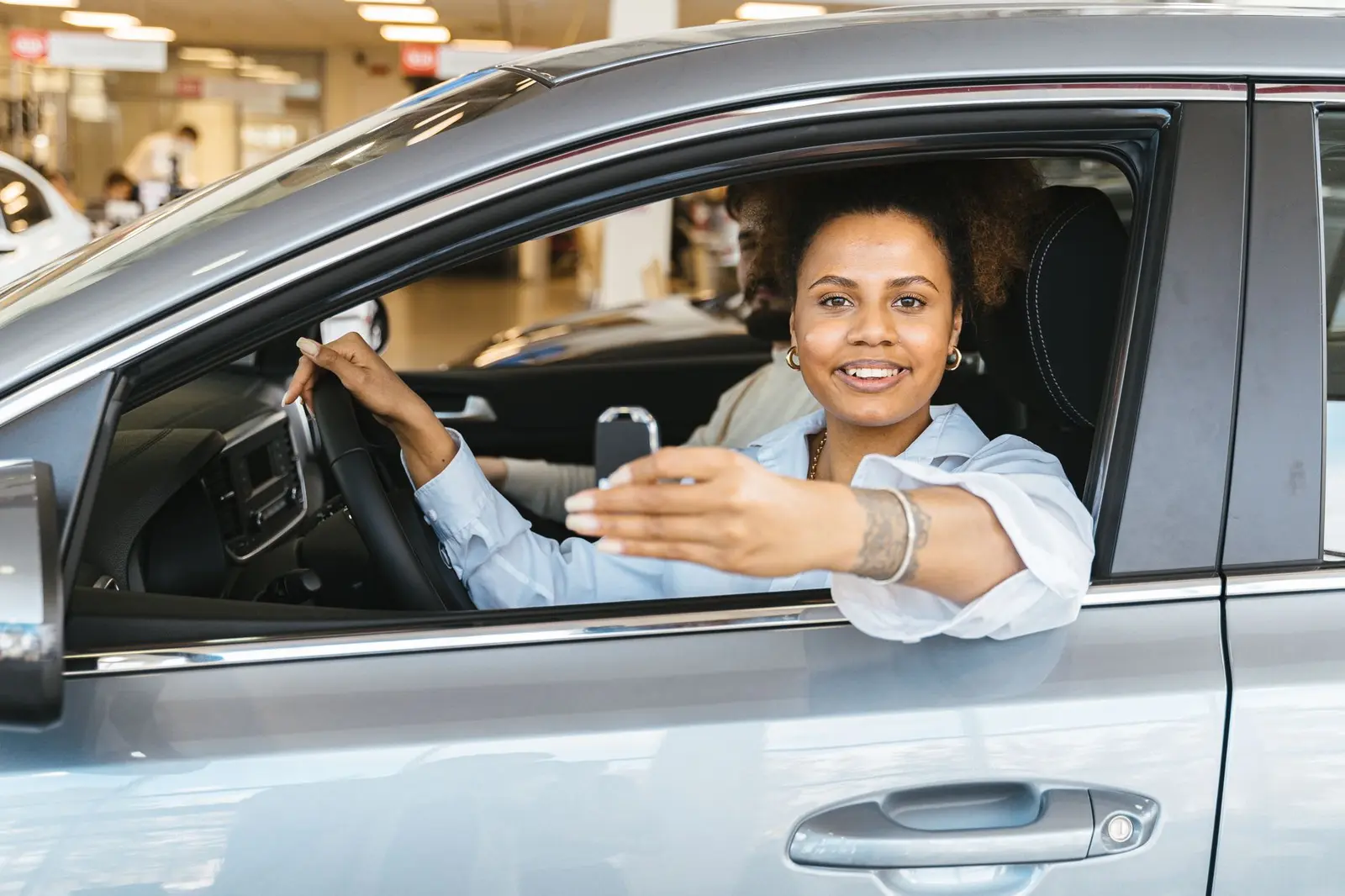 Mujer sonriente en su coche sosteniendo las llaves