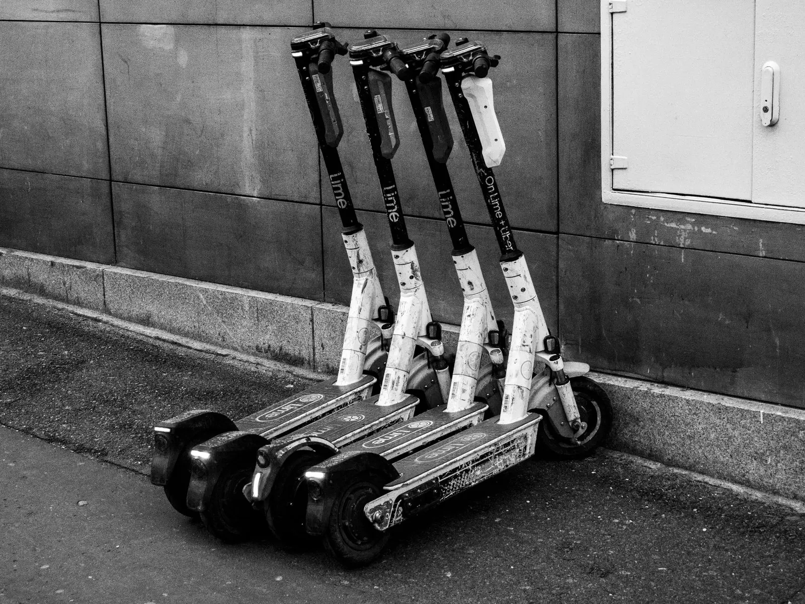 Grupo de patinetes eléctricos aparcados junto a un muro